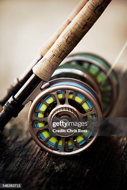 a short focus shot of fly reel resting on wooden plank - fishing reel foto e immagini stock