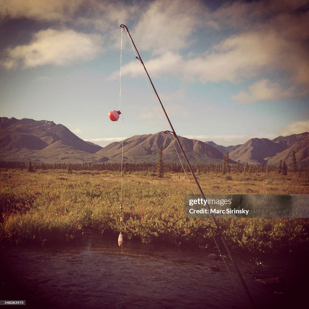 Fishing pole with stream and mountains in the background.  Near Denali National Park, Alaska.
