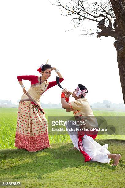 bihu man blowing on a pepa while bihu woman looks on - bihu stock pictures, royalty-free photos & images