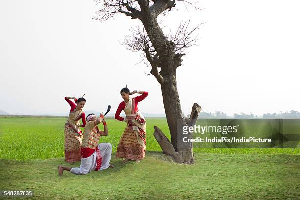 bihu man playing on a pepa while bihu women dance to his tune - bihu fotografías e imágenes de stock