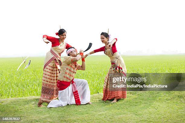 bihu man playing on a pepa while bihu women dance to his tune - bihu stock pictures, royalty-free photos & images