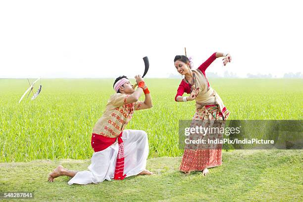 bihu man blowing on a pepa while bihu woman dances to his tune - bihu stock pictures, royalty-free photos & images