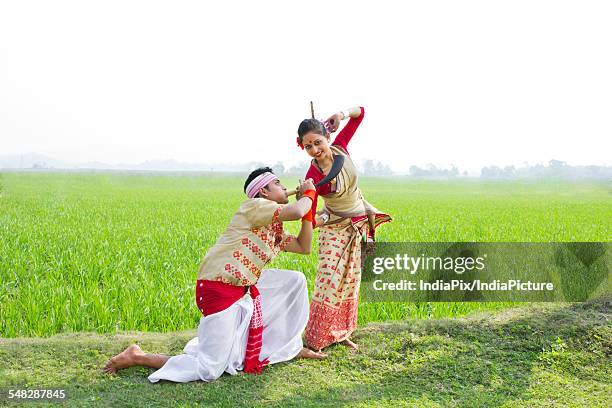 bihu man blowing on a pepa while bihu woman dances to his tune - bihu stock pictures, royalty-free photos & images