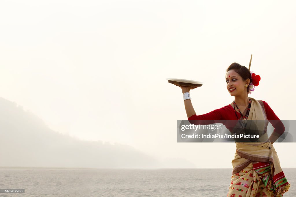 Bihu woman dancing with a brass plate