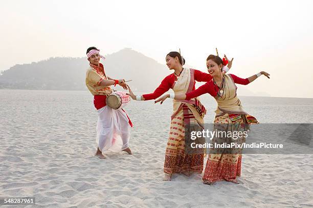 bihu women dancing as bihu man plays on a dhol - bihu fotografías e imágenes de stock