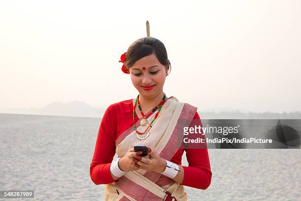 bihu woman reading an sms on a mobile phone - bihu stock pictures, royalty-free photos & images