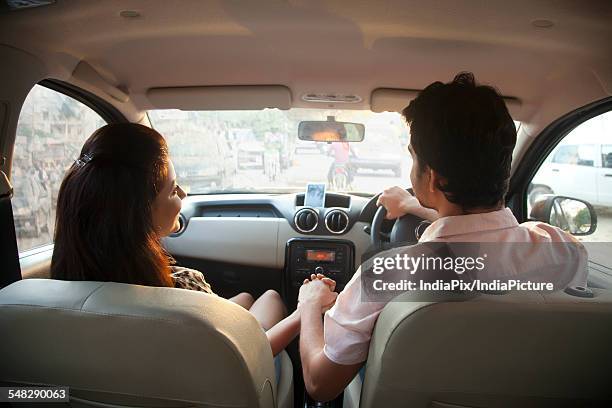 rear view of loving coupe holding hand in car - holding hands in car stock pictures, royalty-free photos & images