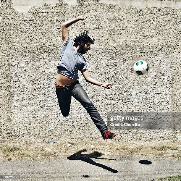 man playing football in the street - street football stock pictures, royalty-free photos & images