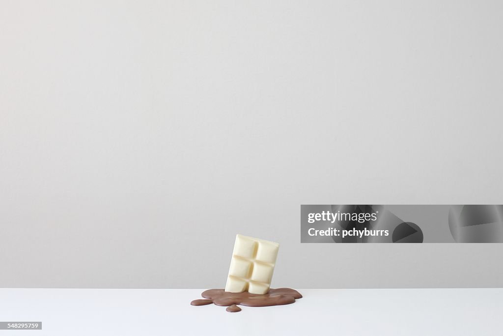 Conceptual bar of white chocolate in a pool of melted milk chocolate