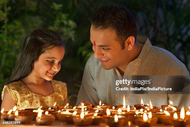 father and daughter lighting diyas - diwali family stock pictures, royalty-free photos & images