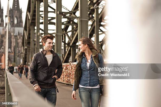 germany, cologne, young couple walking on hohenzollern bridge - keulen stockfoto's en -beelden
