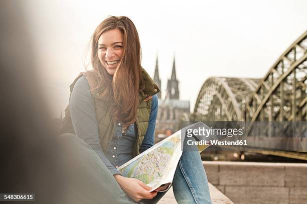 germany, cologne, portrait of smiling young woman with city map on knee - nrw karte stock-fotos und bilder