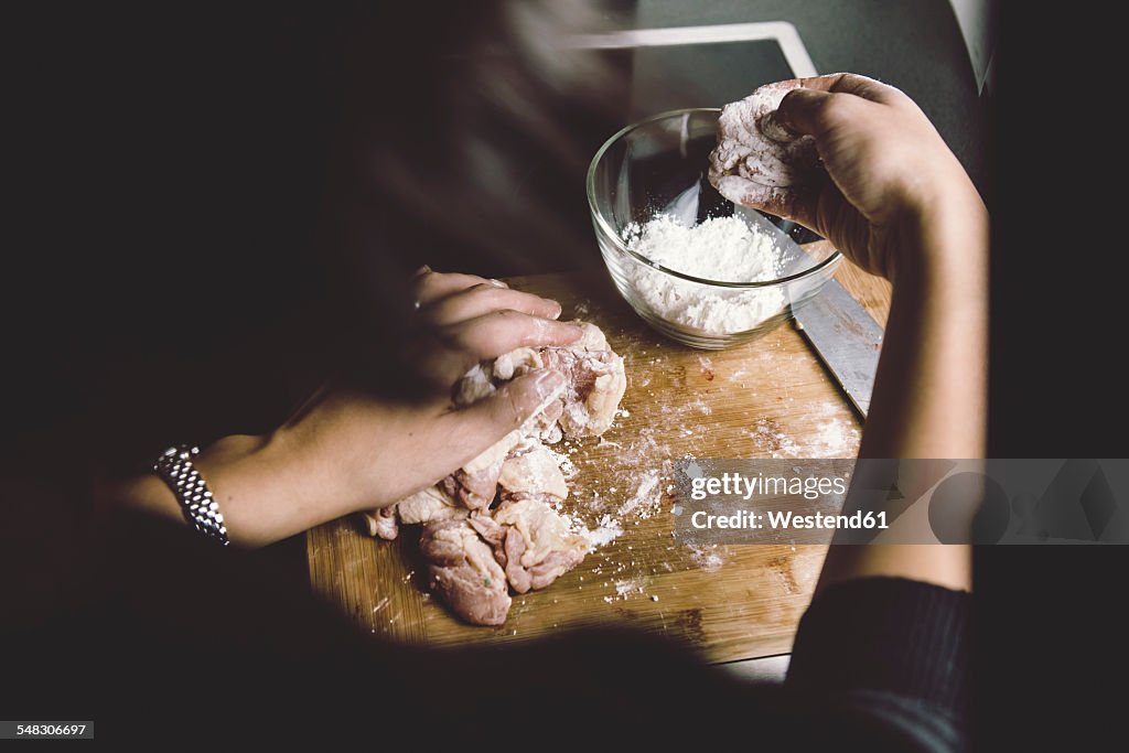 Woman coating chicken with corn starch