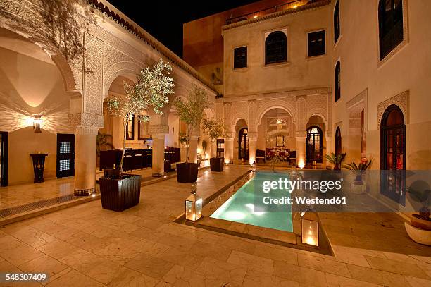 morocco, fes, hotel riad fes, courtyard with lightened pool by night - fes morocco stock pictures, royalty-free photos & images