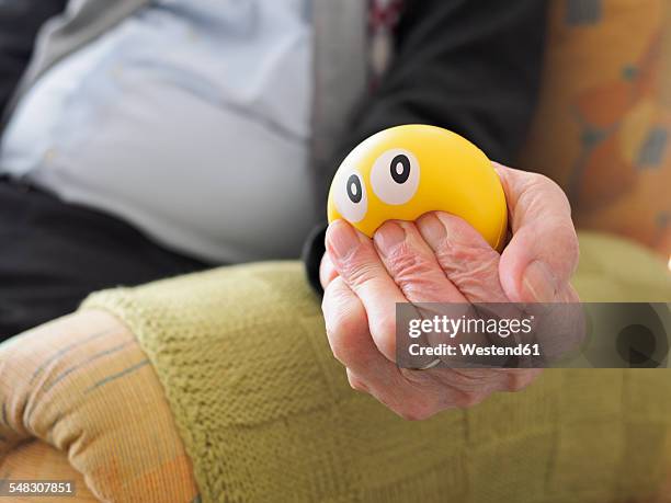 old man in armchair squeezing stress ball - stress ball stock pictures, royalty-free photos & images