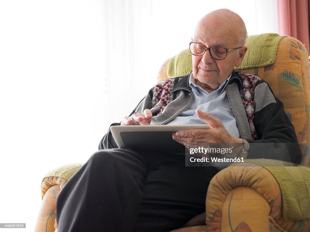 Old man at home using digital tablet