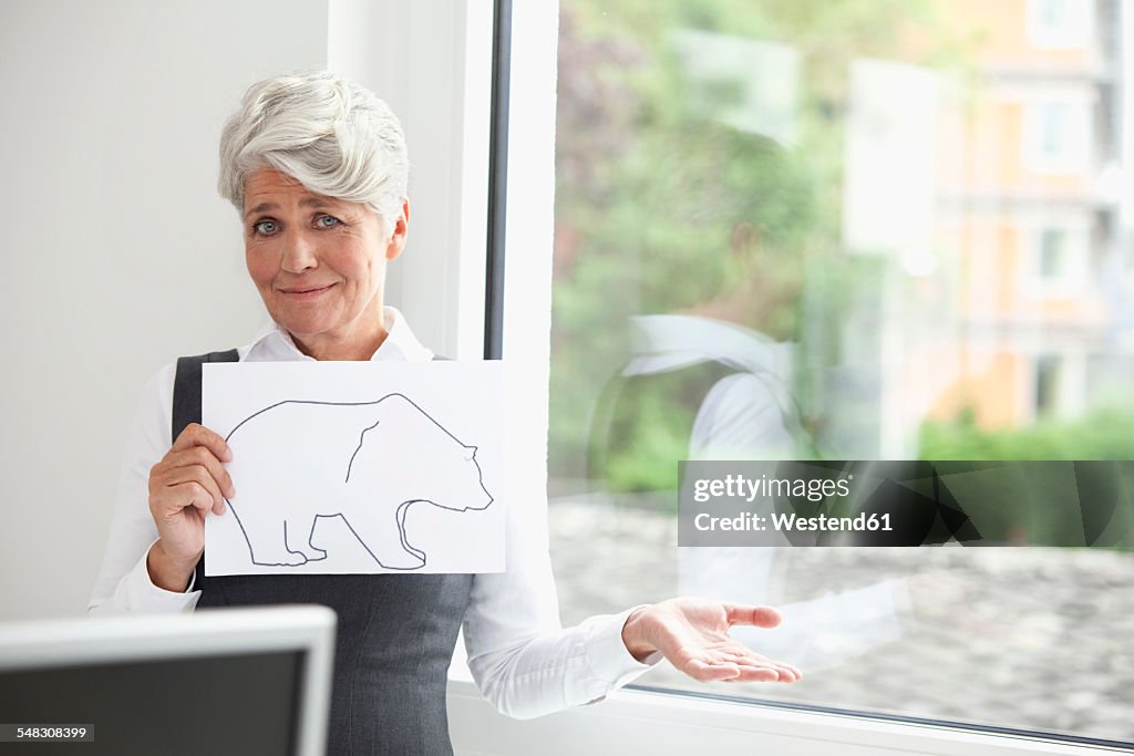 Mature businesswoman holding paper with bear figure