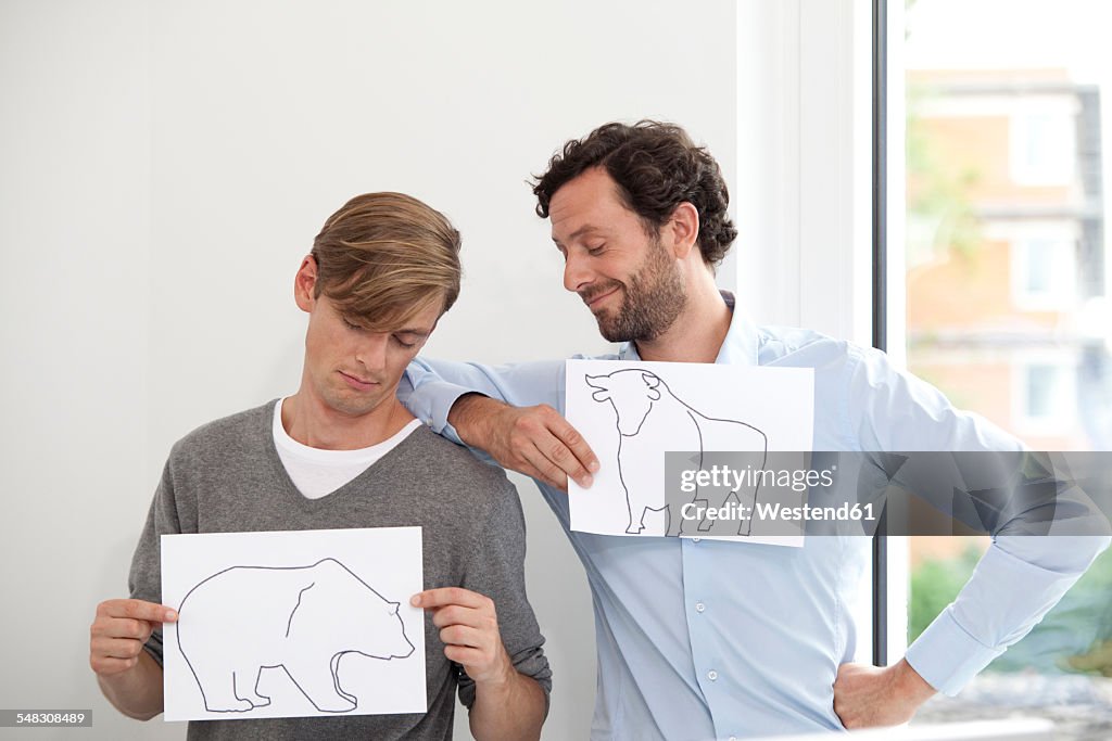 Two businessmen holding papers with bull and bear figure