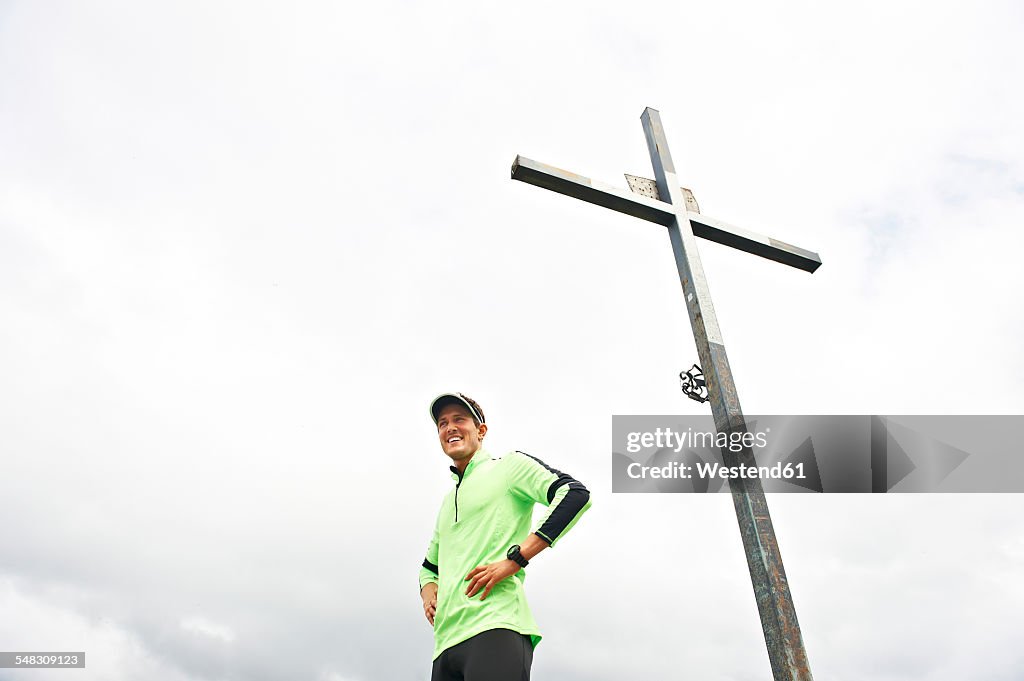 Italy, Trentino, smiling man in sportswear at summit cross