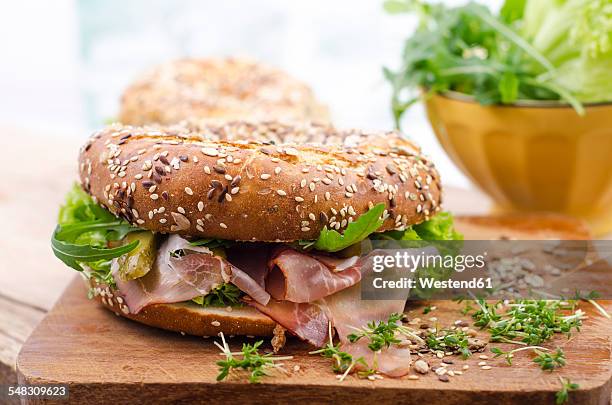 wholemeal bagels with ham, gherkin, lollo rosso, rocket and cress - bagel photos et images de collection