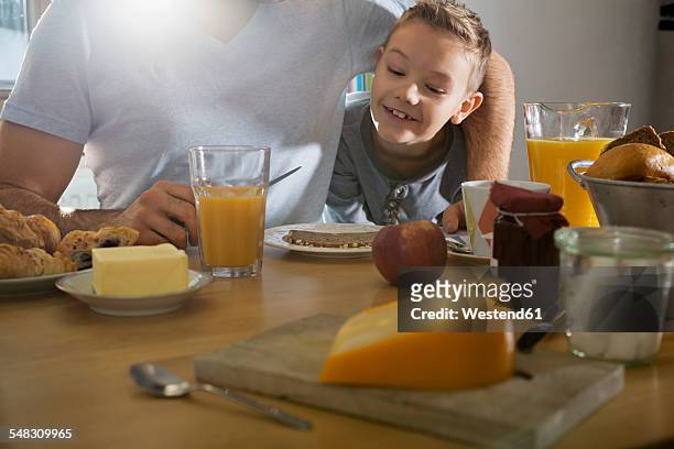 father and son having breakfast together - family orange juice stockfoto's en -beelden