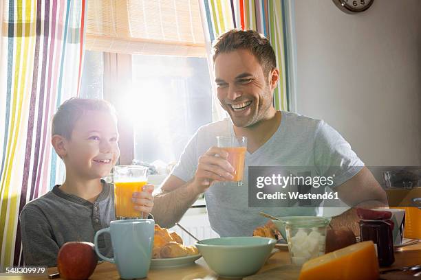 father and son having breakfast together - family orange juice stockfoto's en -beelden