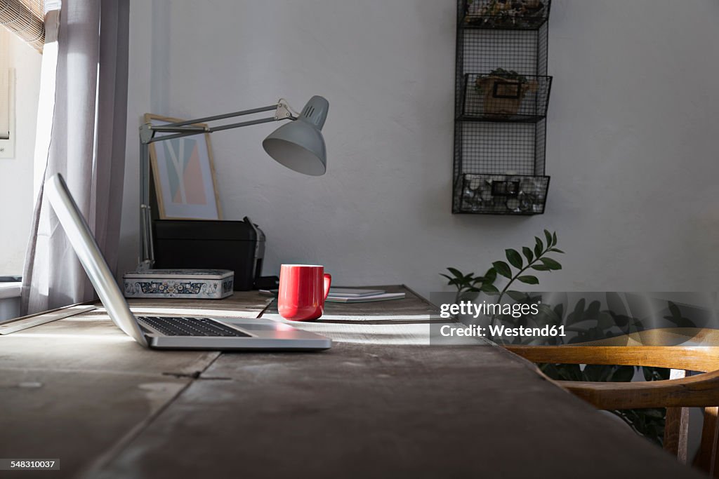 Desk with laptop and coffee cup at home office