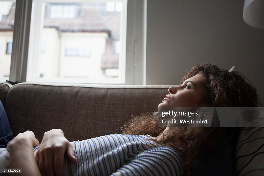 Serious young woman lying on sofa