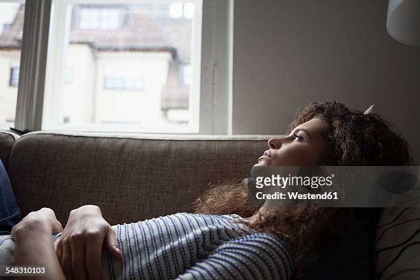 serious young woman lying on sofa - teleurstelling stockfoto's en -beelden