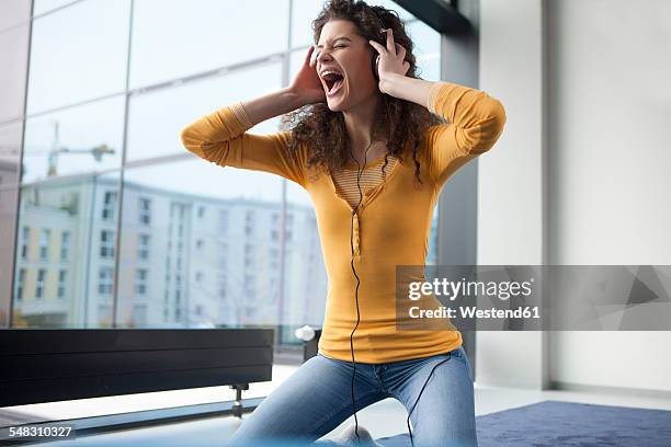 screaming young woman wearing headphones at the window - histeria imagens e fotografias de stock