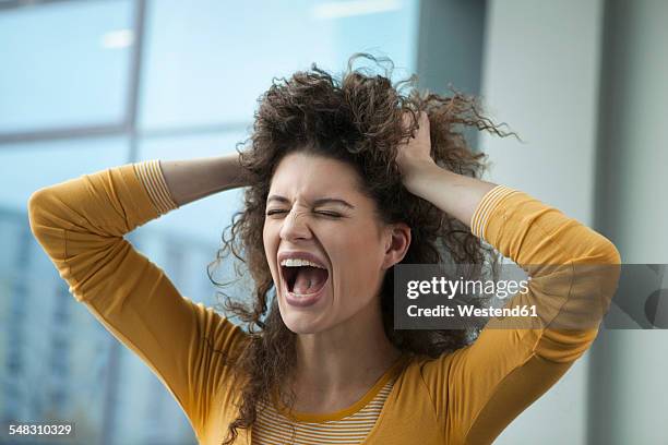 screaming young woman with hands in hair - trotzanfall stock-fotos und bilder