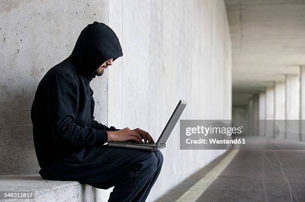 hacker with laptop sitting in an underground car park - hacker stockfoto's en -beelden