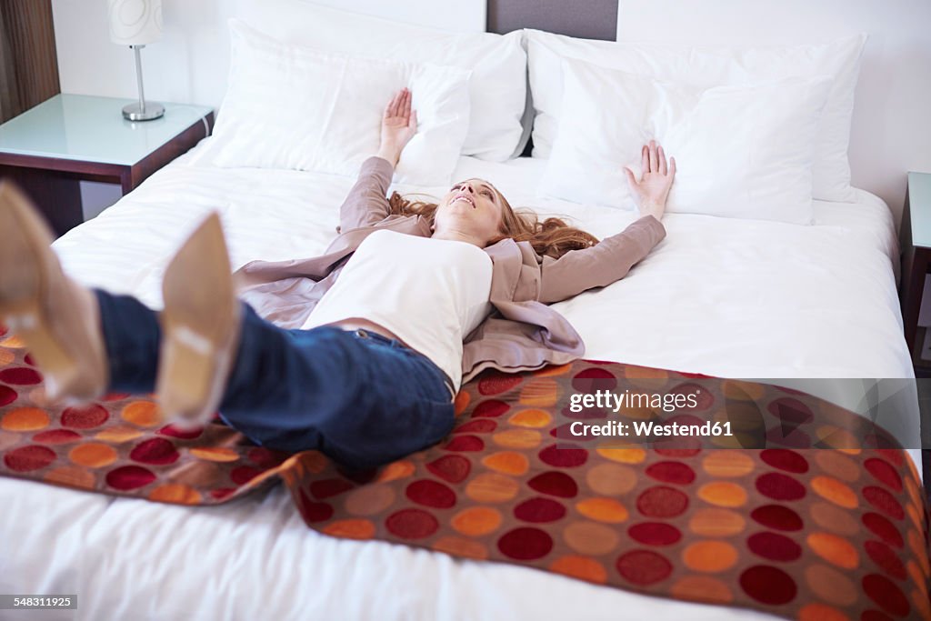 Happy woman falling backwards on hotel bed