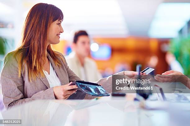 businesswoman paying with credit card at hotel recption - inside bank stock pictures, royalty-free photos & images