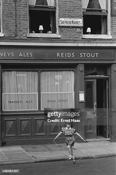 Young girl using a skipping rope outside a public house in Shepherd Market, Mayfair, London, circa 1953.