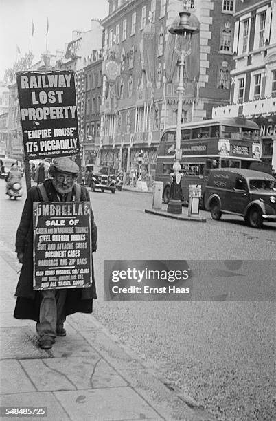 Man carries a sandwich board advertising lost property for sale, Mayfair, London, circa 1953.