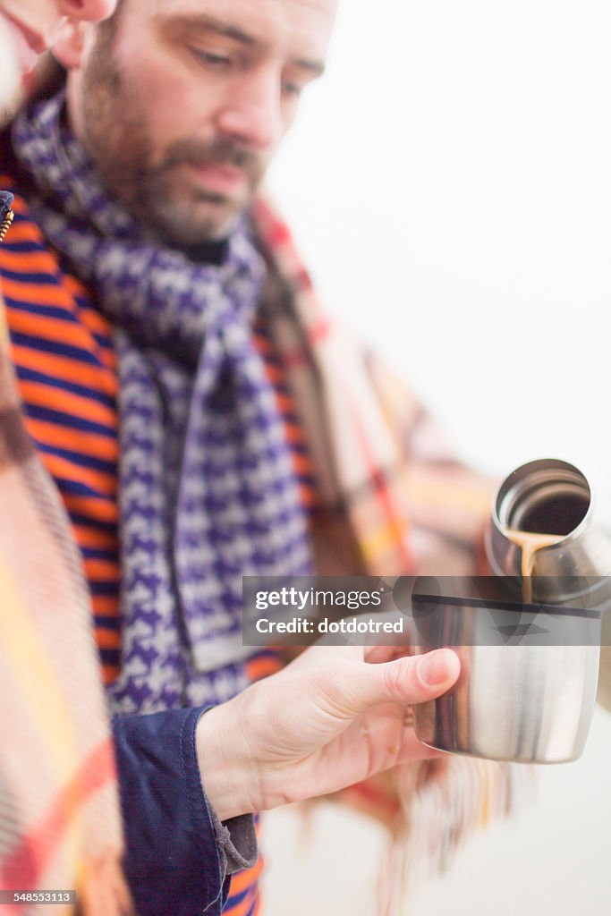 Couple on beach, drinking hot drink from drinks flask