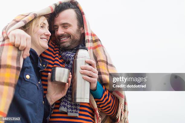 couple outdoors, under blanket, drinking hot drink from drinks flask - couple winter stock pictures, royalty-free photos & images