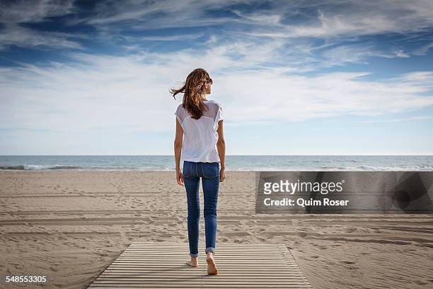 rear view of mid adult woman strolling on beach, castelldefels, catalonia, spain - woman full body behind stock pictures, royalty-free photos & images