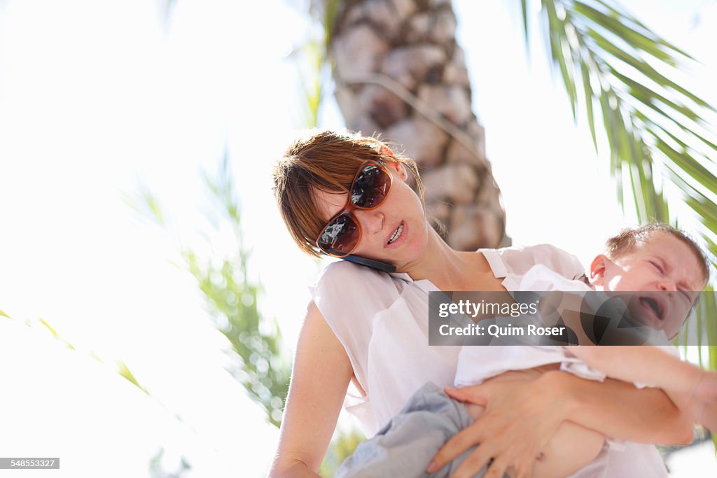 Mid adult woman holding crying toddler daughter, Castelldefels, Catalonia, Spain