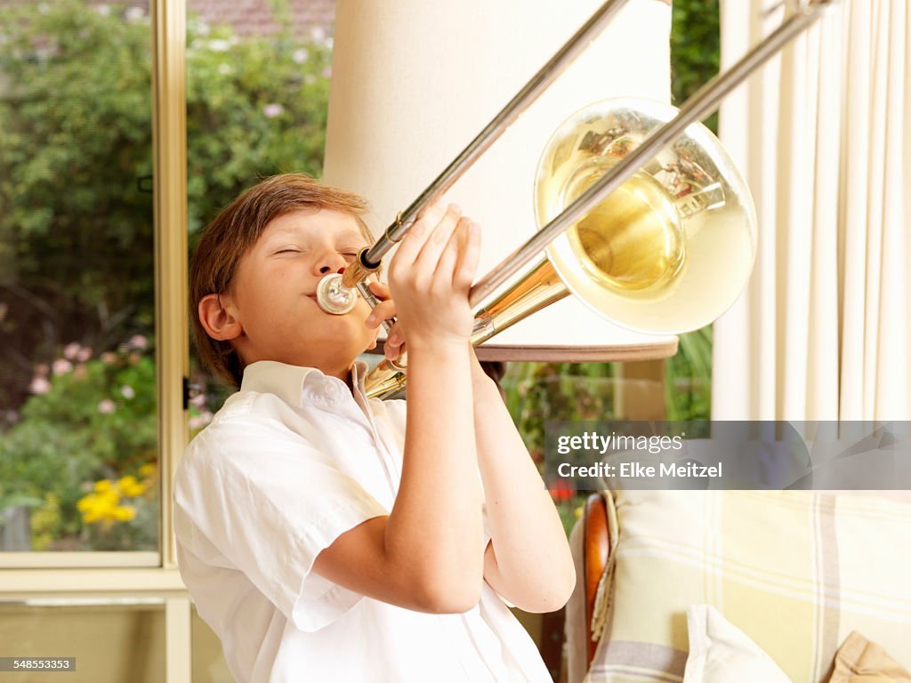 Boy practicing trombone in sitting room