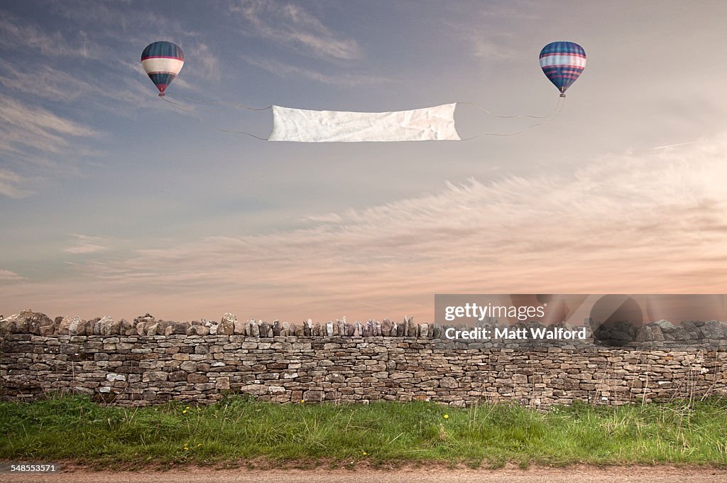 Banner between two hot air balloons over a Cotswold stone wall
