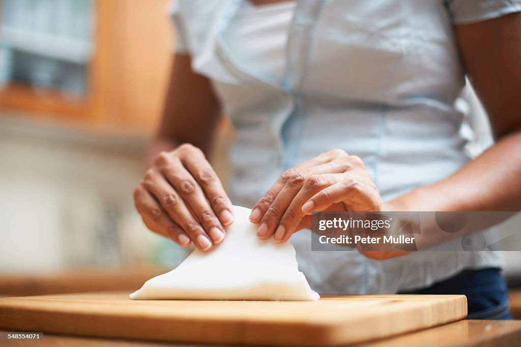 Womans hands making pastry on chopping board