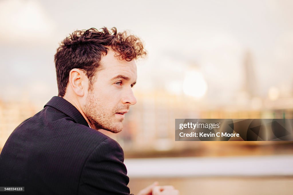 Businessman gazing from Thames riverside, London, UK