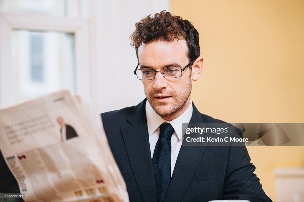 Young businessman reading morning newspaper at home