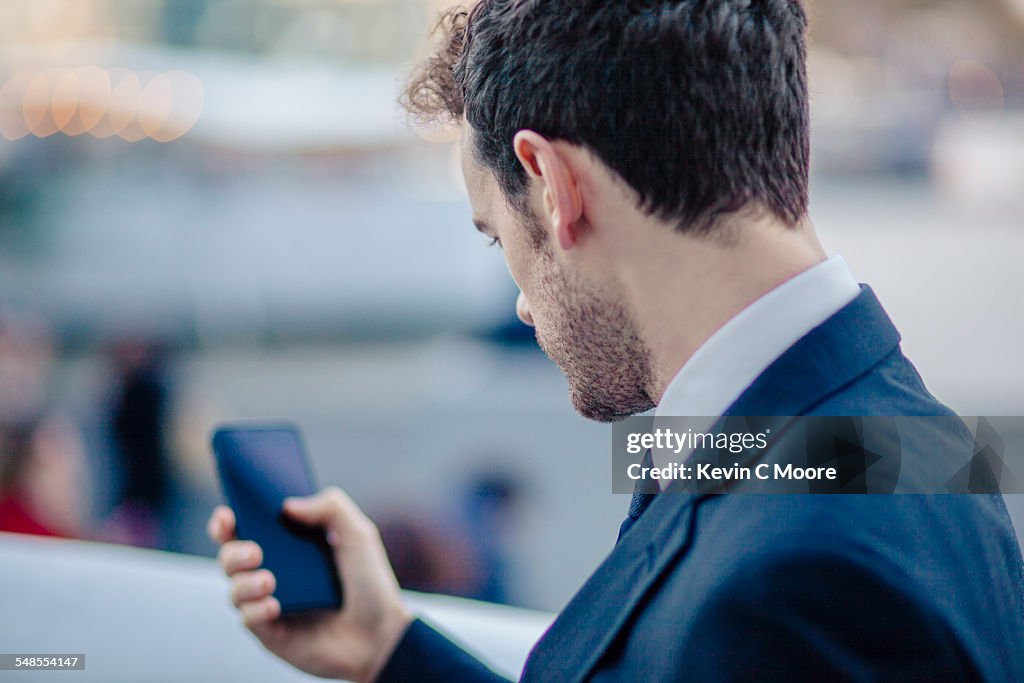 Over the shoulder view of businessman texting on smartphone