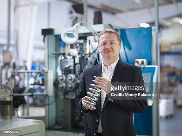 business director holding spring in automotive factory, portrait - car engineer stock-fotos und bilder