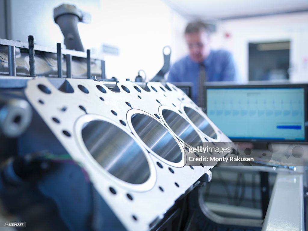 Engineer inspecting automotive engine in test facility