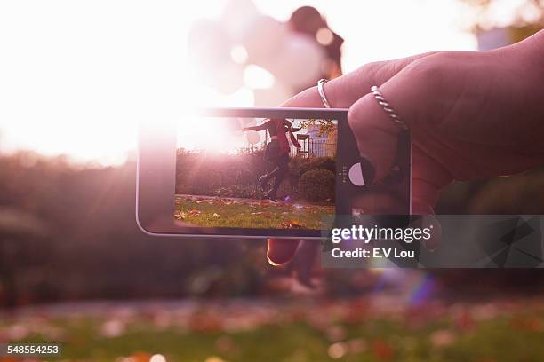 hand holding camera, showing woman jumping - digitalkamera bildschirm stock-fotos und bilder