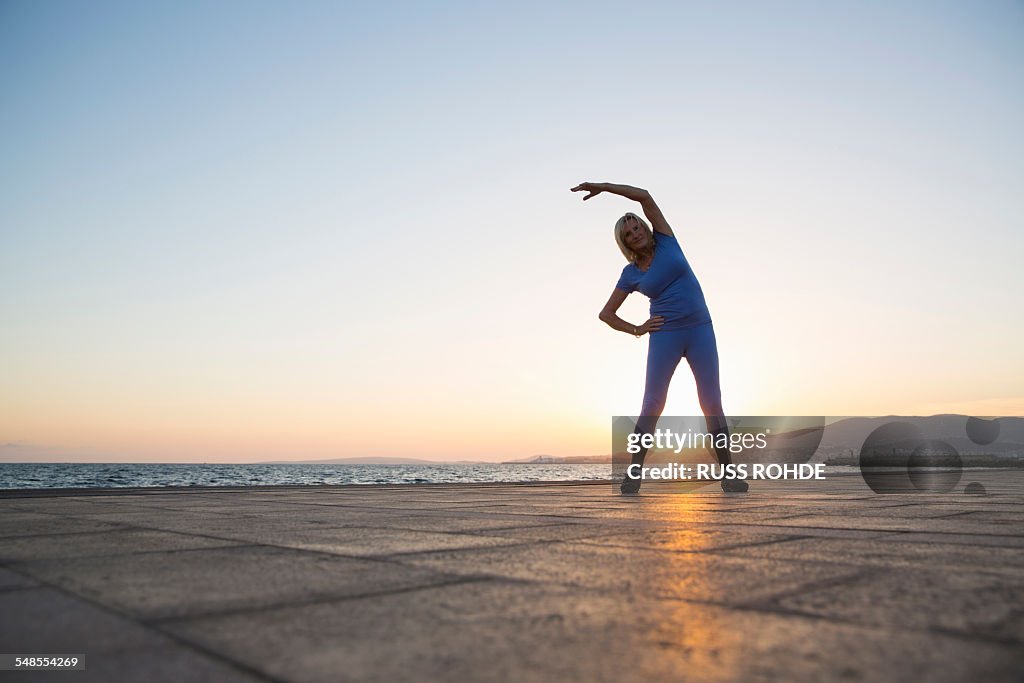 Senior woman stretching by beach